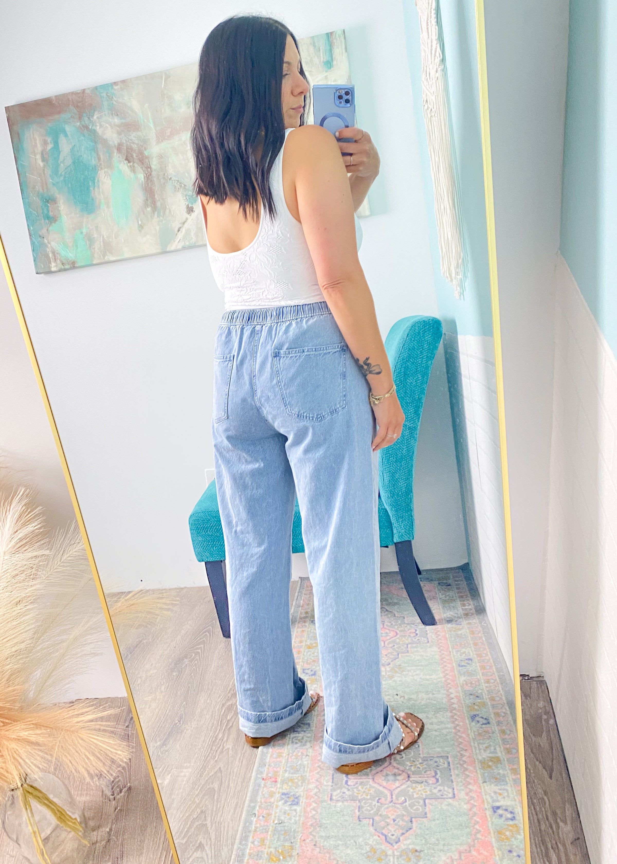 Woman trying on jeans in front of a full-length mirror.