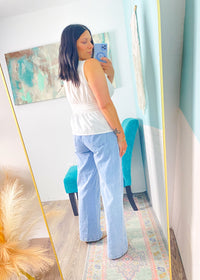 Woman taking a mirror selfie in a room with a large floor mirror, colorful rug, and abstract painting.