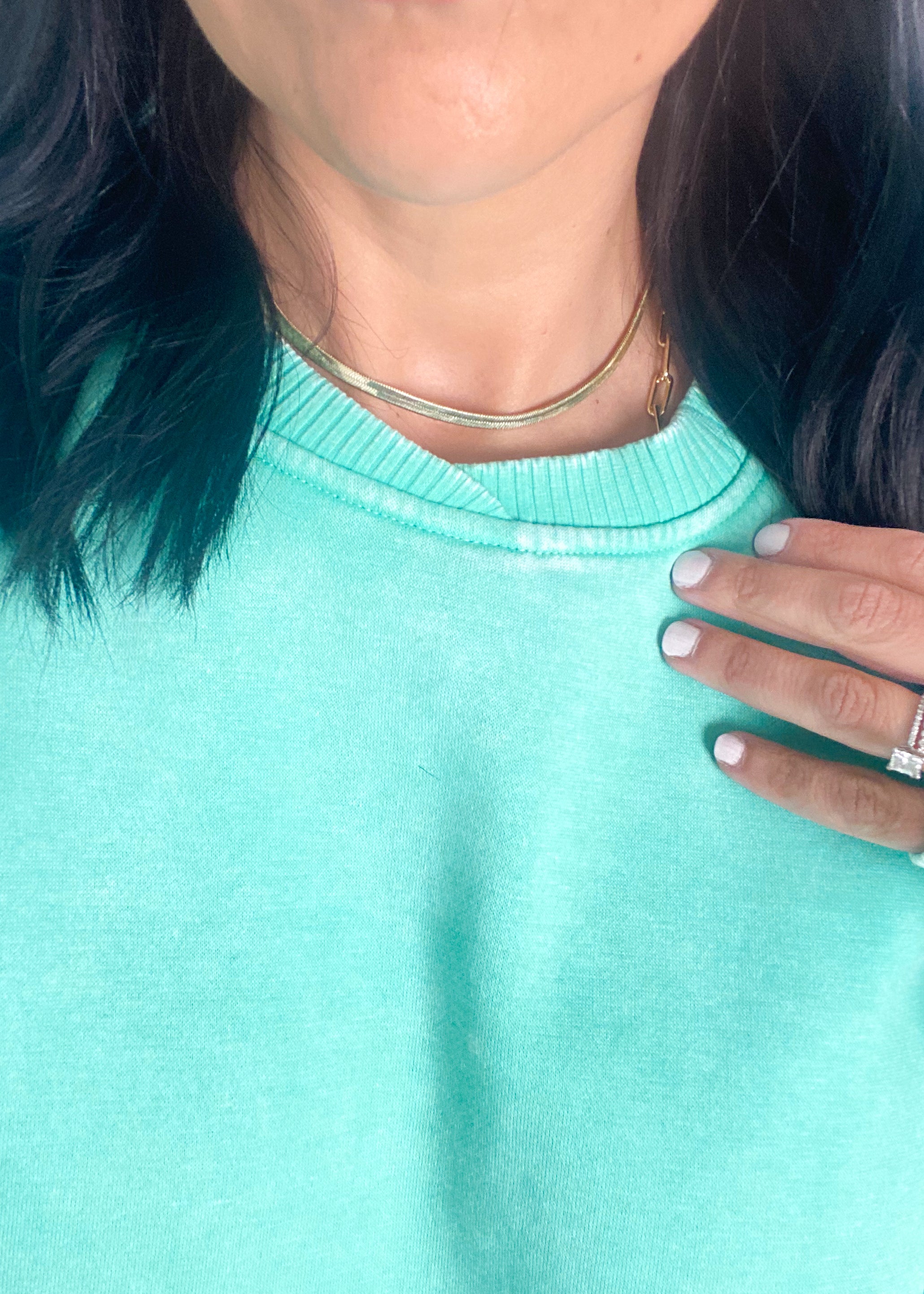 Person wearing a mint green sweatshirt with a close-up of the neckline.
