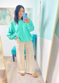 Person wearing a mint green sweatshirt and striped pants taking a mirror selfie.