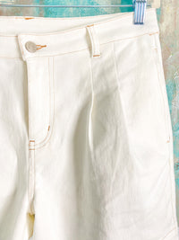 White shorts with a button on a textured blue background