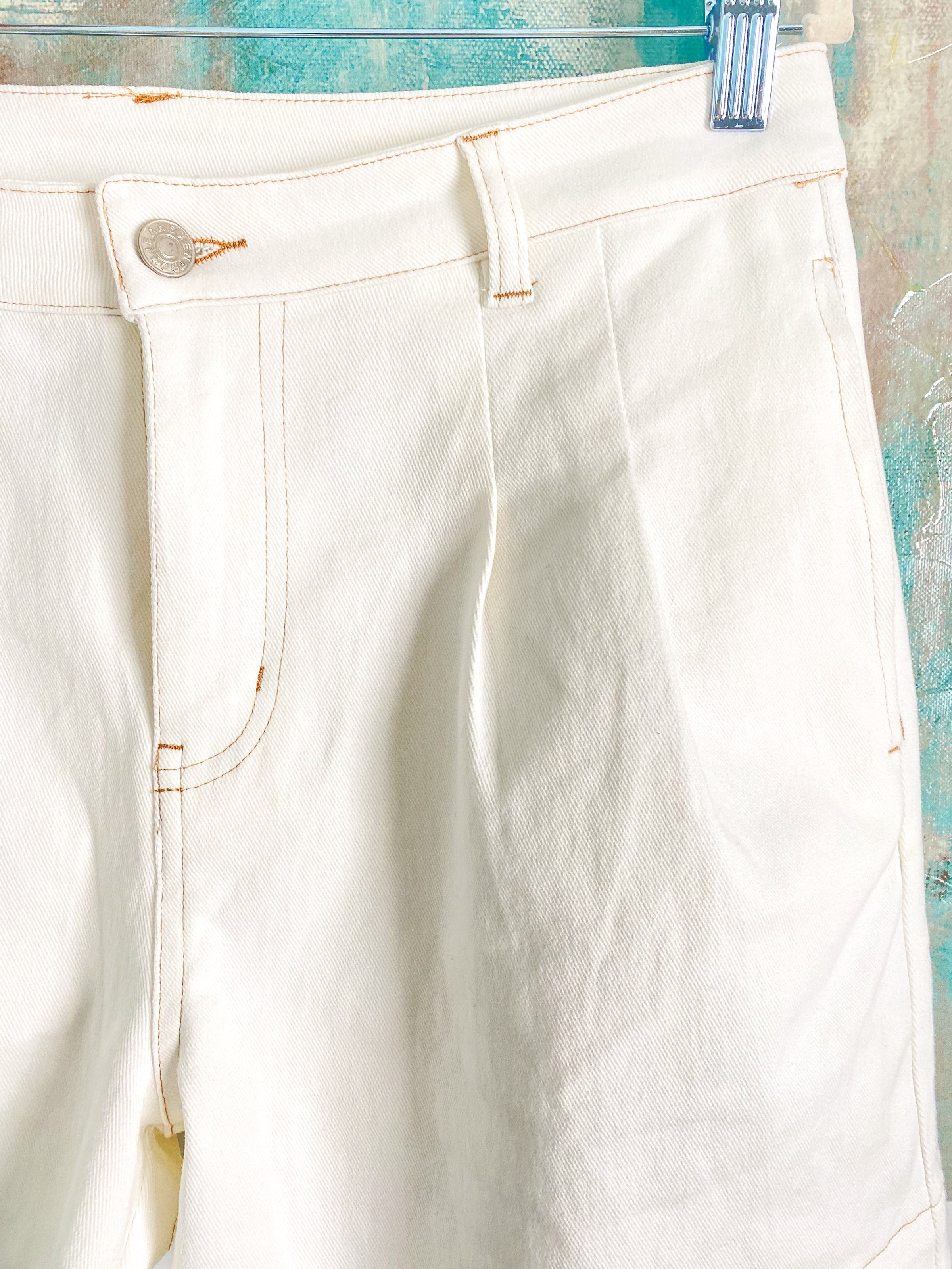 White shorts with a button on a textured blue background